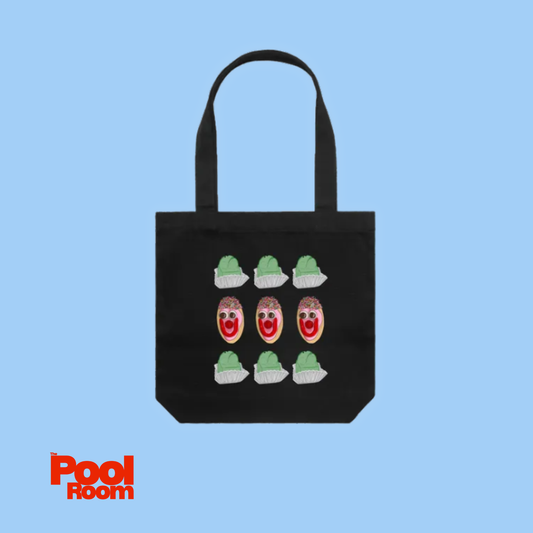 Blue background with black cotton tote bag featuring hand-drawn Smiley Bikkie and Frog Cake illustrations. Designed by The Pool Room.